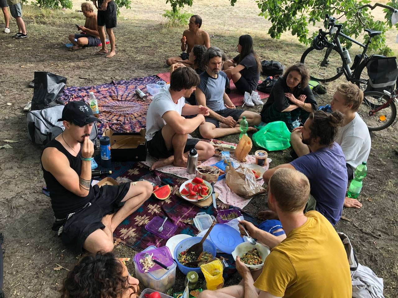 group of people sitting on the ground eating together